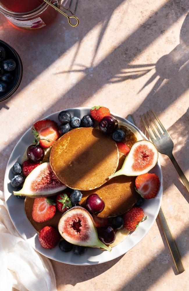 Healthy breakfast bowl of fresh fruit, including figs, blueberries, strawberries, cherries and papaya.