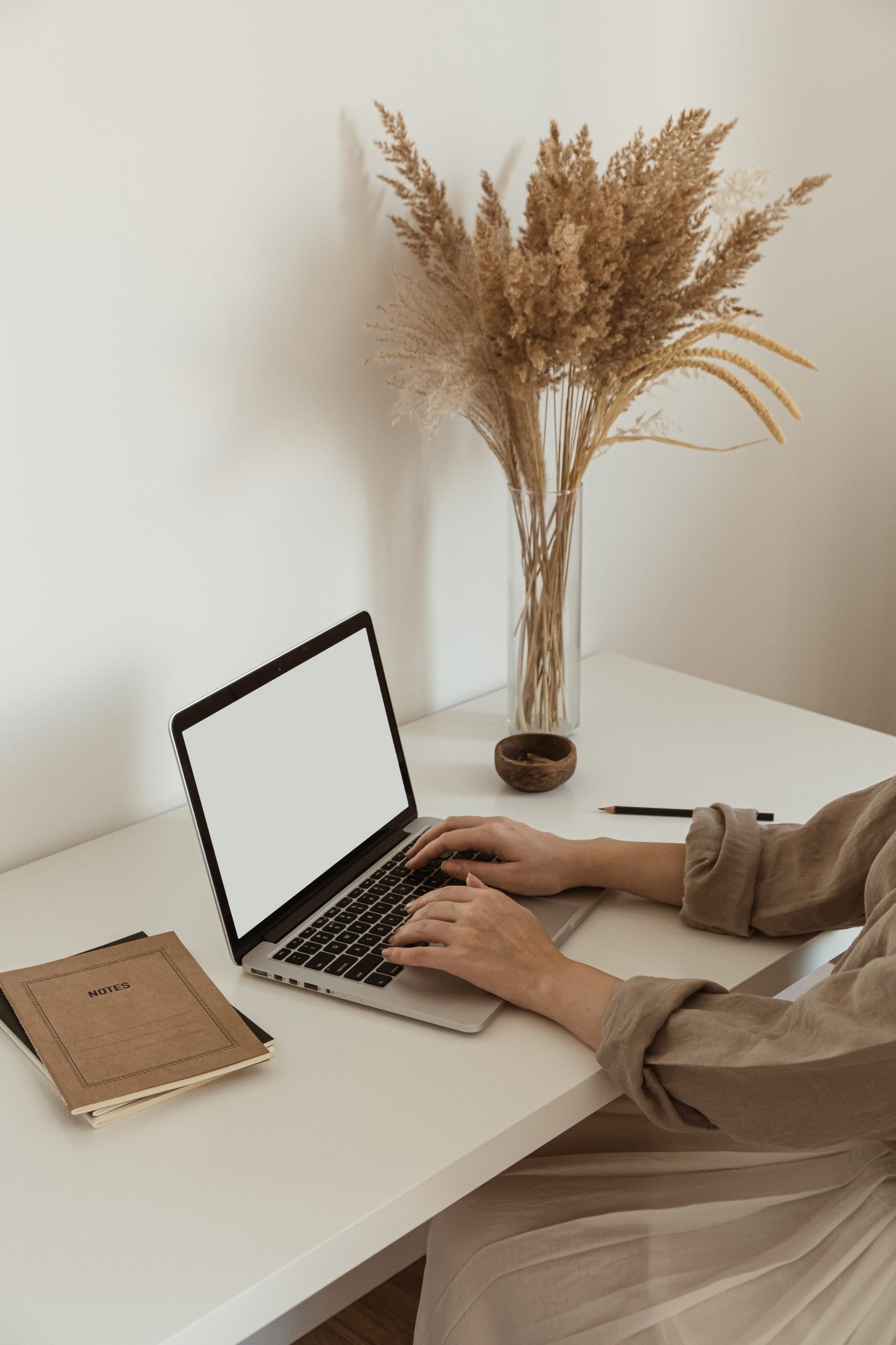 Beautiful woman working, typing on an apple laptop in a cozy minimalist home